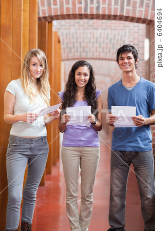Portrait of smiling students holding a piece of paper 6404694