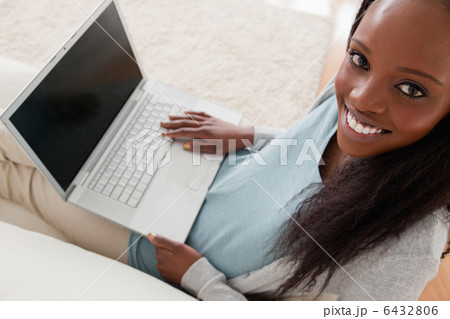 Smiling woman with laptop on sofa 6432806