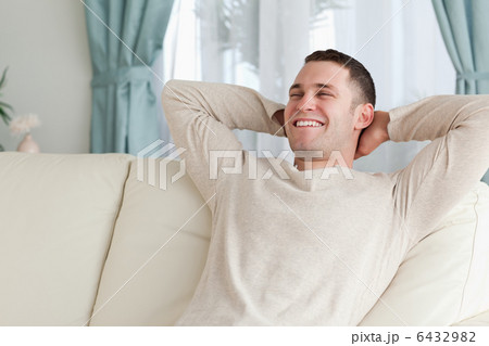 Laughing man relaxing on a sofa 6432982