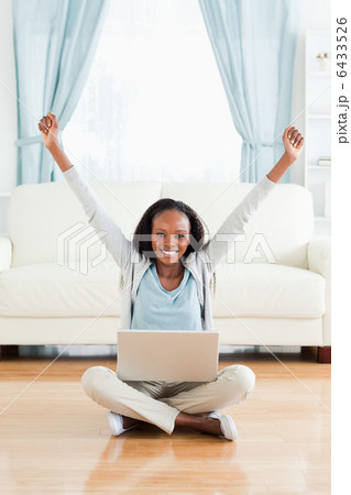 Woman stretching while sitting on the floor with her notebook Woman stretching while sitting on the floor with her notebook 6433526