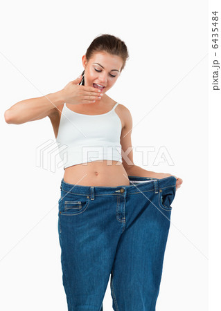 Portrait of a suprised woman wearing too large jeans 6435484