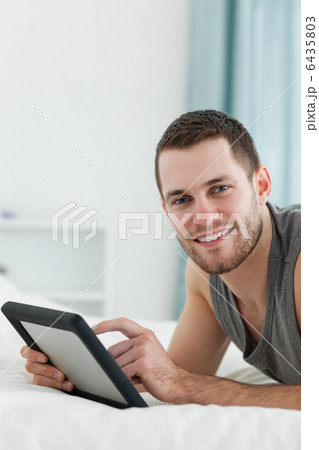 Portrait of an attractive man using a tablet computer while lyin Portrait of an attractive man using a tablet computer while lyin 6435803