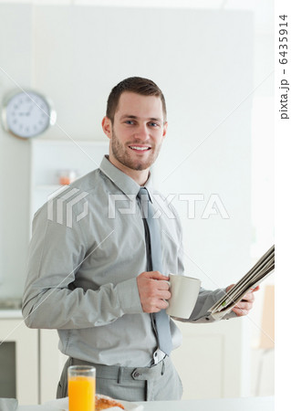 Portrait of a smiling businessman reading the news while having 6435914