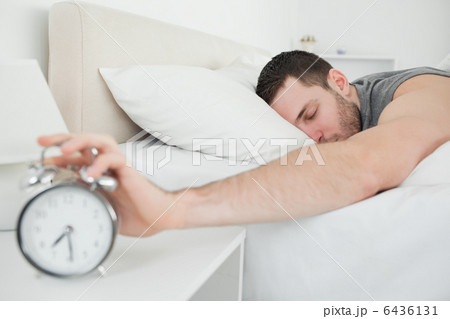 Sleeping handsome man being awakened by an alarm clock 6436131