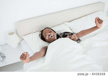 Woman yawning and stretching her arms while waking up 6436308