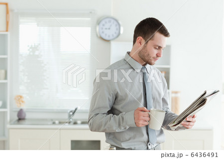 Young businessman reading the news while having breakfast Young businessman reading the news while having breakfast 6436491