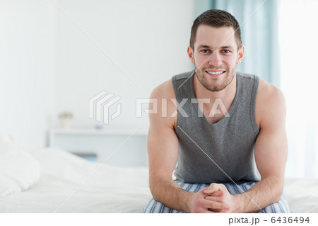 Smiling man sitting on his bed Smiling man sitting on his bed 6436494