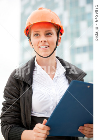 Young architect-woman wearing a protective helmet standing on th Young architect-woman wearing a protective helmet standing on th 6459831