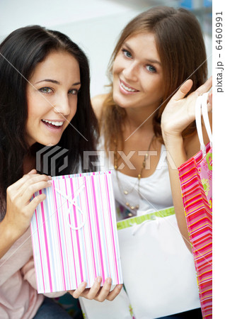 Two excited shopping woman resting on bench at shopping mall loo 6460991