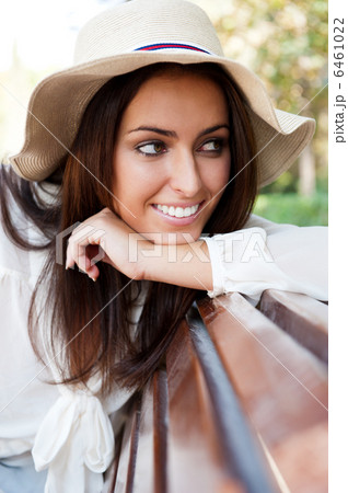 Portrait of a sexy young female smiling in a park while sitting 6461022