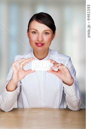 Young businesswoman showing her business card - sitting at her o Young businesswoman showing her business card - sitting at her o 6461393