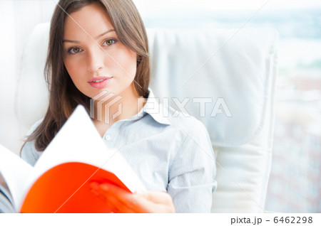 Portrait of a sensual young woman reading a novel while sitting 6462298