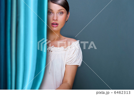 Closeup of young, pretty woman standing near curtain and holding 6462313
