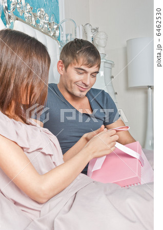 Young happy couple presenting gift in bed Young happy couple presenting gift in bed 6462530