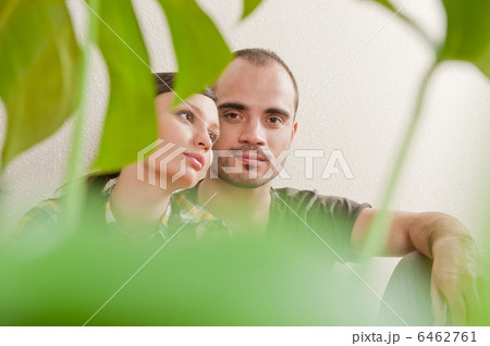 Attractive young adult couple sitting close on hardwood floor in 6462761