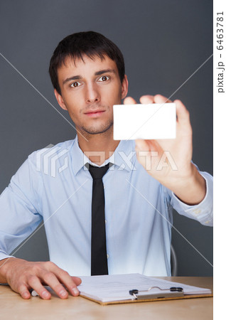 Business man handing a blank business card over grey background 6463781