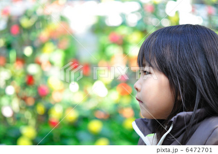 真剣な眼差しで見つめる女の子 花バック の写真素材