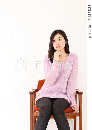 椅子に座る女性 悩む の写真素材