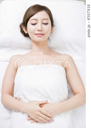 バスタオル姿で仰向けになっている女性の写真素材