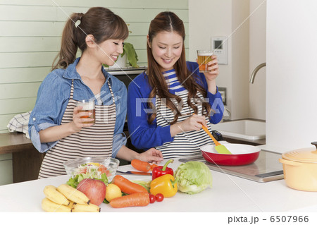ビールを飲みながら料理をしている2人の女性の写真素材