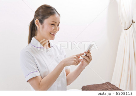 スマートフォンを操作している白衣の女性 スマートフォンを操作している白衣の女性 6508113