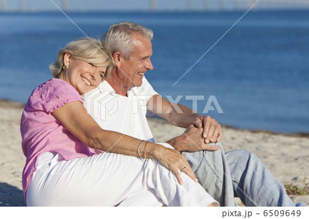 Happy Romantic Senior Couple Sitting Together on Beach 6509649