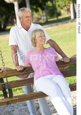 Happy Senior Couple Smiling Outside in Sunshine on Park Swing 6509740