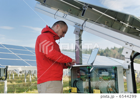 engineer using laptop at solar panels plant field 6544299