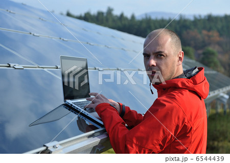 engineer using laptop at solar panels plant field 6544439