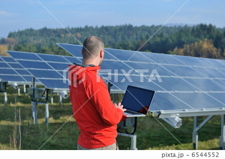 engineer using laptop at solar panels plant field 6544552