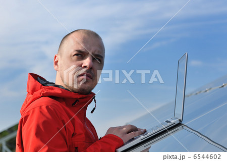 engineer using laptop at solar panels plant field 6544602