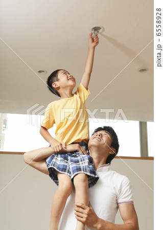 天井の電球を付け替える男の子と父親 天井の電球を付け替える男の子と父親 6558928