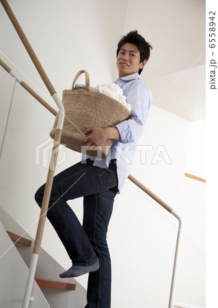 洗濯籠を持って階段を上がる男性 6558942