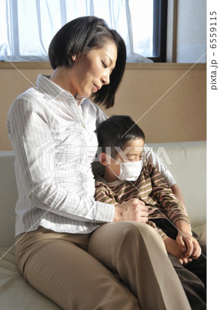 マスクを着けた男の子の肩を抱く母親 6559115