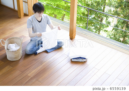 窓際で洗濯物をたたむ男性 6559139