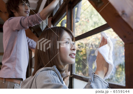 窓ガラスを一緒に拭く若いカップル 窓ガラスを一緒に拭く若いカップル 6559144