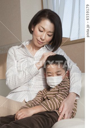 マスクを着けた男の子の肩を抱く母親 6559179