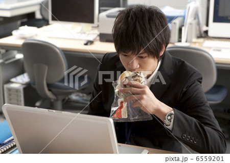 パソコンを見てパンを食べるスーツ姿の男性 パソコンを見てパンを食べるスーツ姿の男性 6559201
