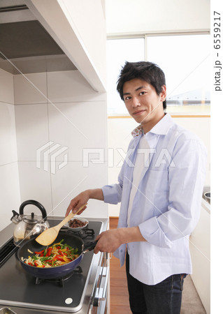 フライパンで野菜を炒める男性 6559217