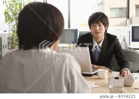 上司に話し掛けるスーツ姿の若い男性 上司に話し掛けるスーツ姿の若い男性 6559225