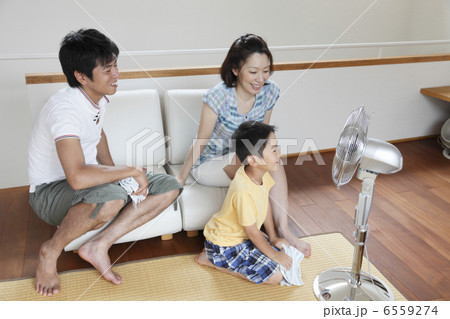 扇風機に近づく男の子とソファに座る両親 扇風機に近づく男の子とソファに座る両親 6559274