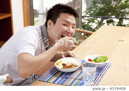 大きな口を開けて食べようとする男性 6559408