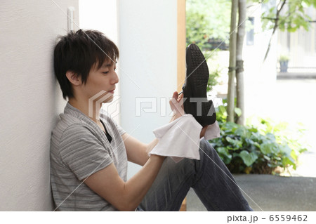 壁にもたれて靴を磨く男性 6559462