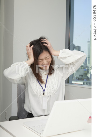 職場で頭を抱えて顔をしかめる若い女性 6559476