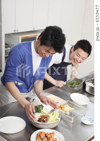 鍋の準備をする男性と覗き込む男性 6559477