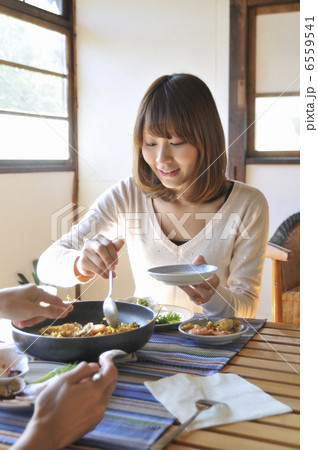 料理を取り分ける若い女性の写真素材
