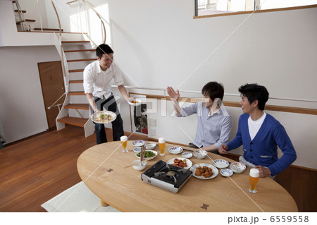 料理を運ぶ男性と座って待つ男性 6559558