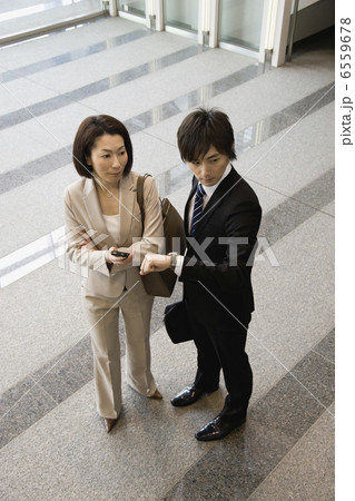 時間を確認するスーツ姿の男女 6559678