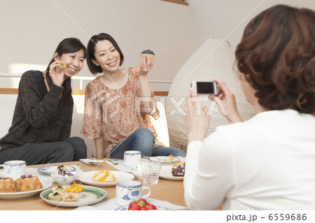 菓子を携帯電話で撮影をする三人の女性 6559686