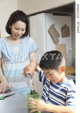 容器に液体を詰め替える男の子と母親 6559866